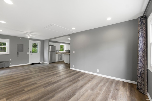 unfurnished living room featuring attic access, healthy amount of natural light, dark wood-type flooring, baseboards, and recessed lighting