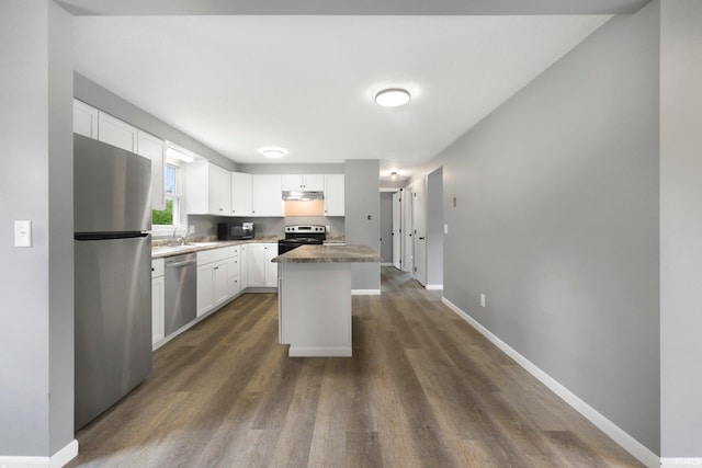 kitchen featuring appliances with stainless steel finishes, under cabinet range hood, dark wood-type flooring, and white cabinets