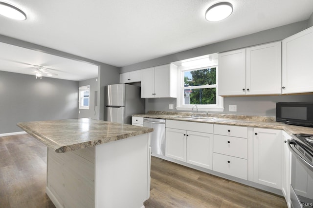 kitchen featuring stainless steel appliances, a sink, wood finished floors, and white cabinets
