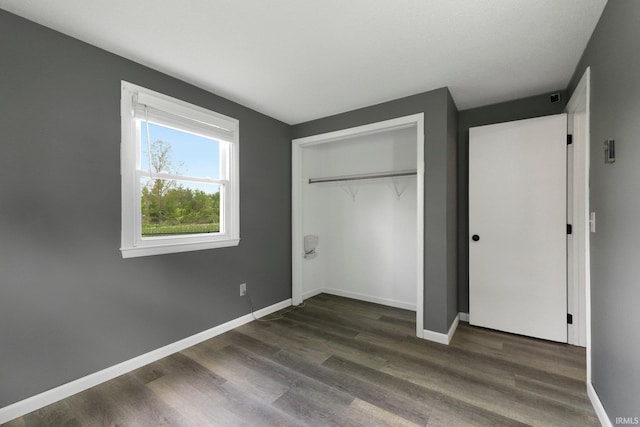 unfurnished bedroom featuring dark wood-style flooring, baseboards, and a closet