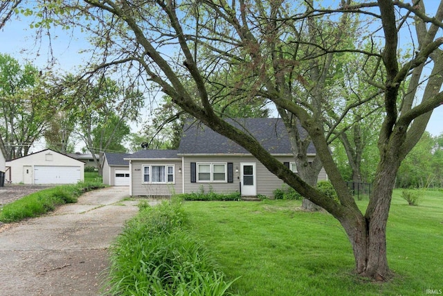 view of front of property with a front yard, a detached garage, and roof with shingles