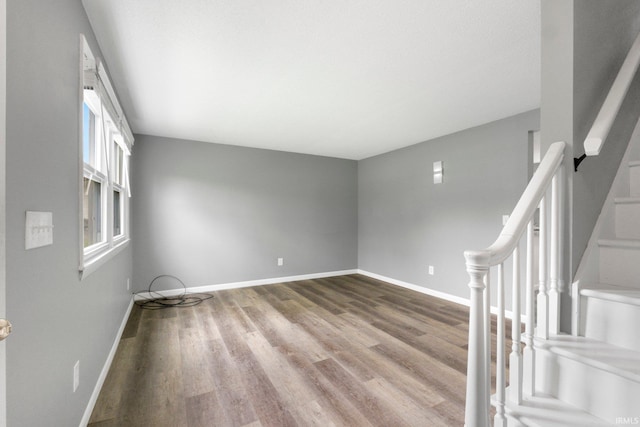unfurnished room with wood finished floors, baseboards, and stairs
