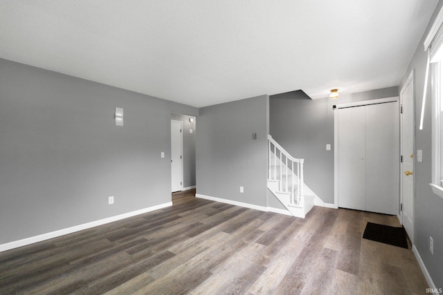 entrance foyer with stairway, dark wood-style flooring, and baseboards