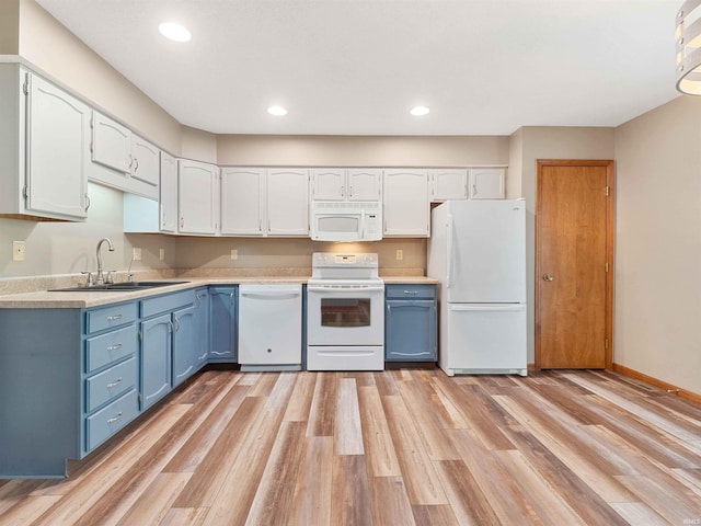kitchen with white appliances, a sink, blue cabinets, white cabinetry, and recessed lighting