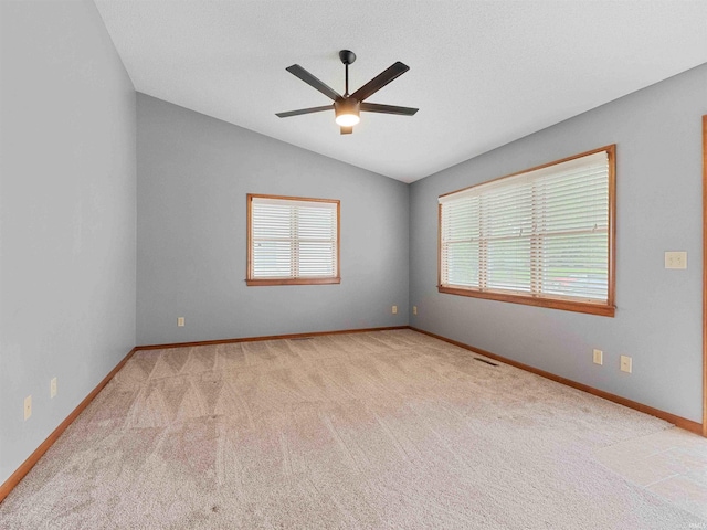 carpeted spare room featuring lofted ceiling, a ceiling fan, and baseboards