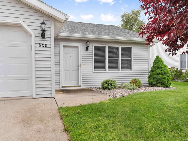 doorway to property featuring a shingled roof, a lawn, and an attached garage
