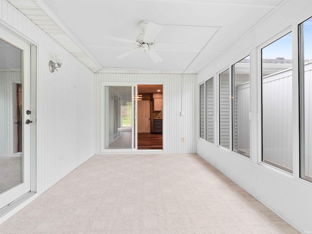 unfurnished sunroom featuring ceiling fan and carpet floors