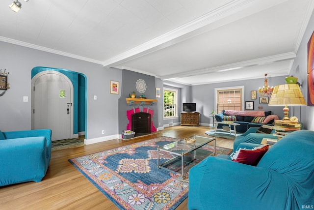 living area featuring wood finished floors, crown molding, baseboards, a chandelier, and arched walkways