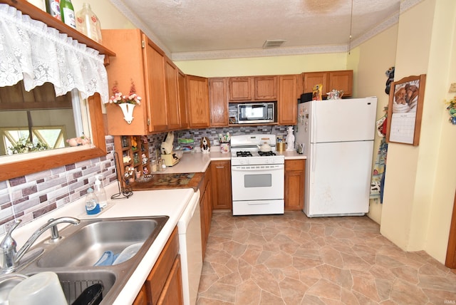 kitchen featuring white appliances, a sink, decorative backsplash, brown cabinets, and a textured ceiling