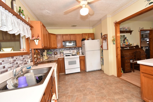 kitchen with white appliances, backsplash, a ceiling fan, brown cabinets, and a sink