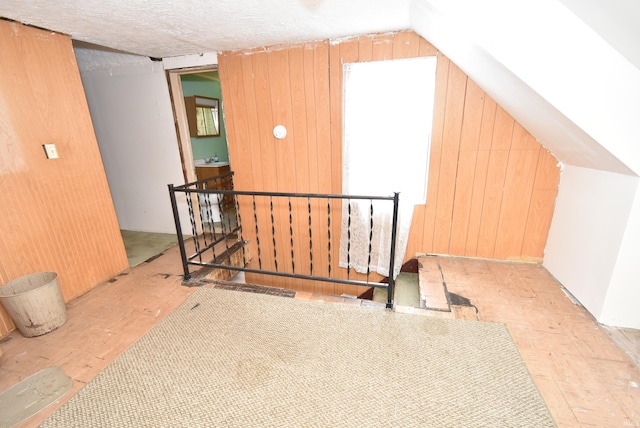 bonus room with wood walls, lofted ceiling, wood finished floors, and healthy amount of natural light