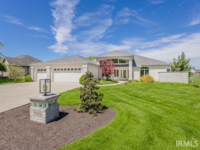 view of front of house featuring a front lawn, driveway, an attached garage, and french doors