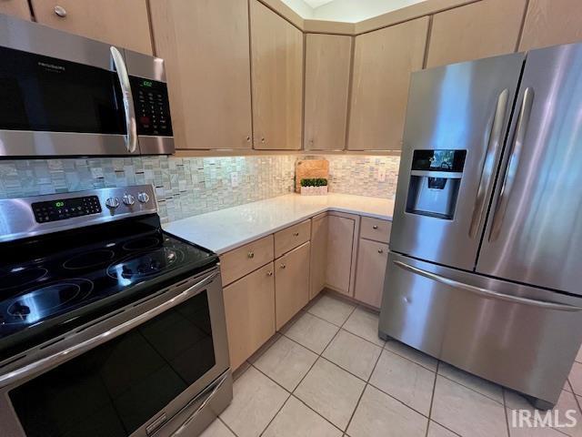 kitchen with stainless steel appliances, light countertops, backsplash, and light tile patterned floors