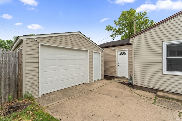 detached garage with concrete driveway and fence