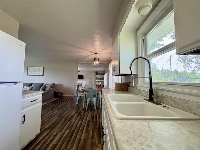 kitchen featuring freestanding refrigerator, a sink, light countertops, and white cabinets