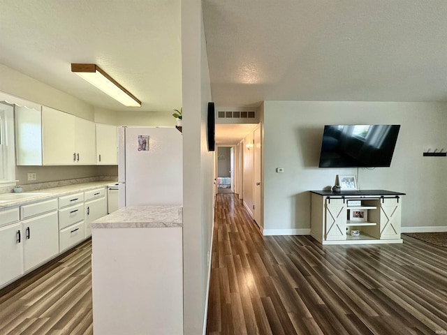 kitchen featuring freestanding refrigerator, dark wood-style flooring, baseboards, and white cabinets