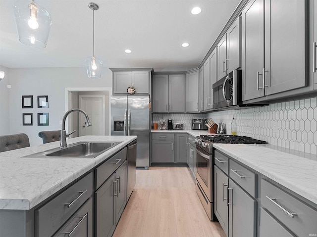 13655 Copper Strike Pass, Fort Wayne, IN 46845 - kitchen with appliances with stainless steel finishes, a sink, gray cabinetry, light wood-style floors, and a center island with sink