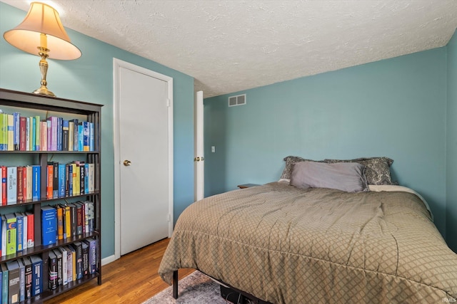 bedroom with wood finished floors and a textured ceiling
