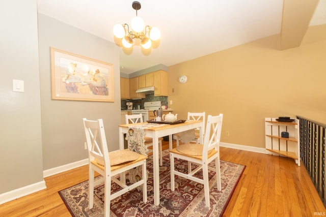 dining area with light wood-type flooring, a chandelier, and baseboards