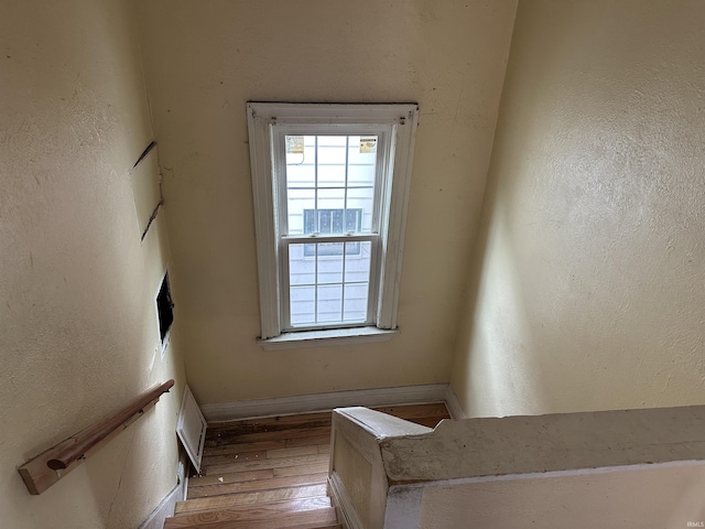 stairway with wood finished floors, healthy amount of natural light, and baseboards