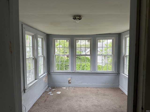 unfurnished sunroom with healthy amount of natural light and carpet floors