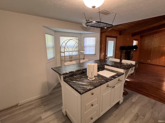 211 Mccutcheon Dr, Lafayette, IN 47909 - kitchen with light wood-style flooring, a center island, white cabinets, wood walls, and baseboards