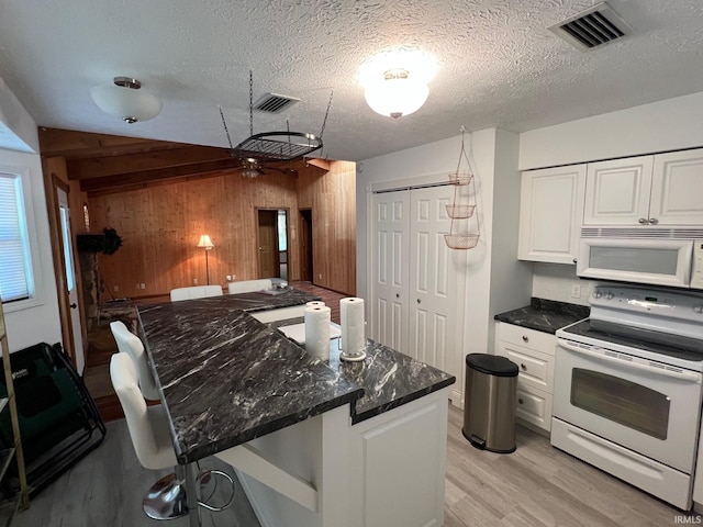 211 Mccutcheon Dr, Lafayette, IN 47909 - kitchen featuring white appliances, wood walls, light wood-style floors, white cabinets, and dark stone countertops