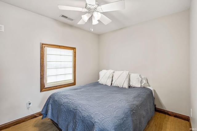 bedroom featuring baseboards, wood finished floors, and ceiling fan