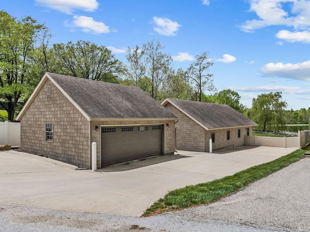 view of front of home featuring a garage, fence, and a shingled roof