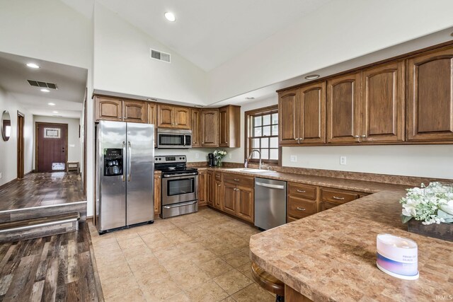 kitchen featuring appliances with stainless steel finishes, a sink, lofted ceiling, recessed lighting, and dark countertops