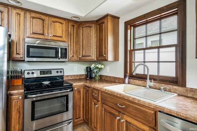 kitchen with stainless steel appliances, a sink, and brown cabinetry