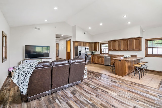 living area featuring light wood-style flooring, recessed lighting, high vaulted ceiling, and baseboards