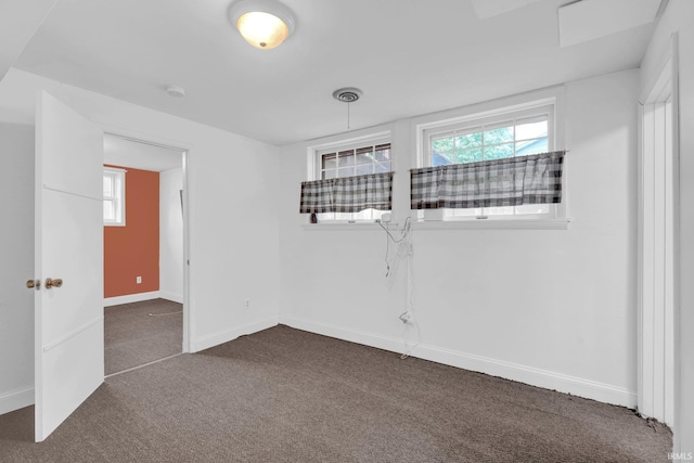 unfurnished room with dark carpet, baseboards, and a smoke detector
