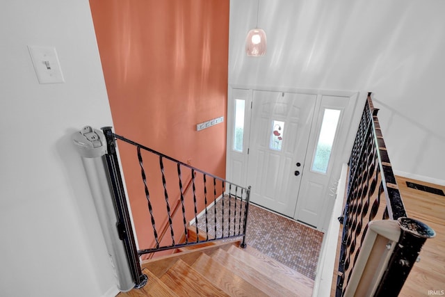 foyer with light wood finished floors, baseboards, and stairway