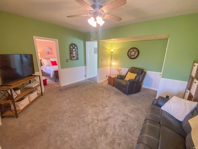 living room featuring wainscoting, a ceiling fan, and carpet