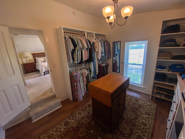 spacious closet with dark wood-style floors and a chandelier