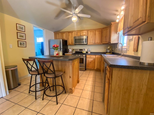 kitchen featuring stainless steel appliances, a sink, a kitchen island, light tile patterned floors, and vaulted ceiling