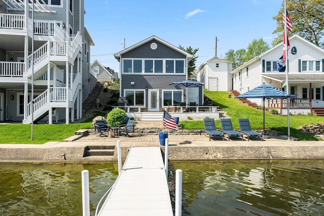 dock area with stairs, a patio, a deck with water view, and a yard