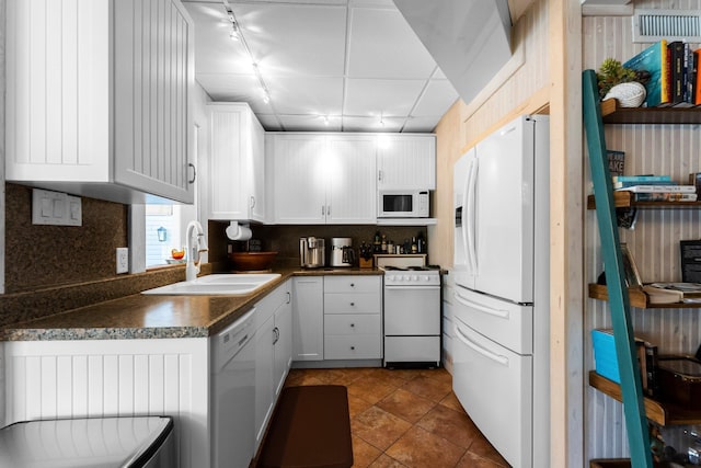 kitchen featuring white appliances, a sink, dark countertops, rail lighting, and tasteful backsplash