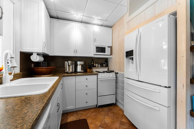 kitchen with white appliances, a sink, white cabinets, and tile patterned flooring