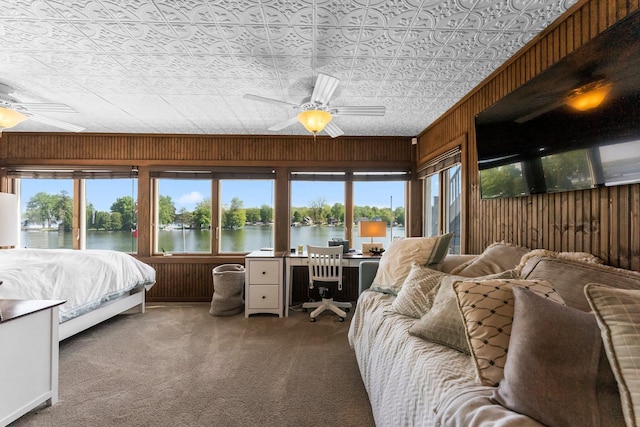 carpeted bedroom with wood walls, an office area, a ceiling fan, access to exterior, and an ornate ceiling