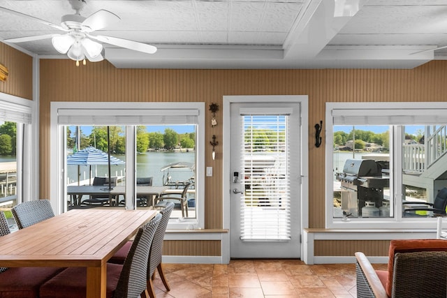 dining room with ceiling fan, a water view, and wallpapered walls