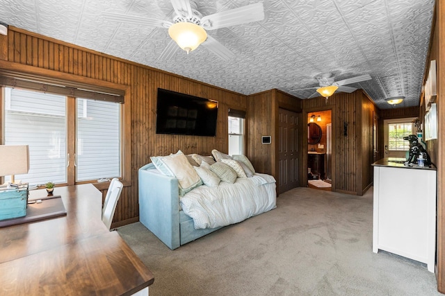 carpeted living area featuring ceiling fan, wood walls, and an ornate ceiling