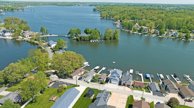 aerial view of property's location with a large body of water, nearby suburban area, and a heavily wooded area