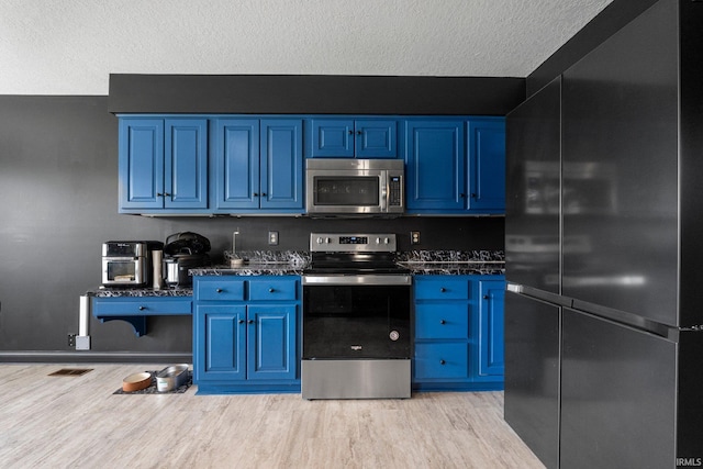 kitchen with stainless steel appliances, light wood-style flooring, blue cabinets, and a textured ceiling