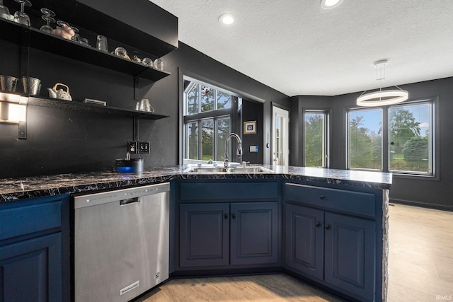 kitchen with stainless steel dishwasher, a sink, blue cabinets, a textured ceiling, and a peninsula