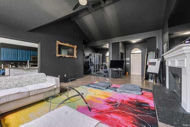 living area with ceiling fan, wood finished floors, a brick fireplace, and baseboards