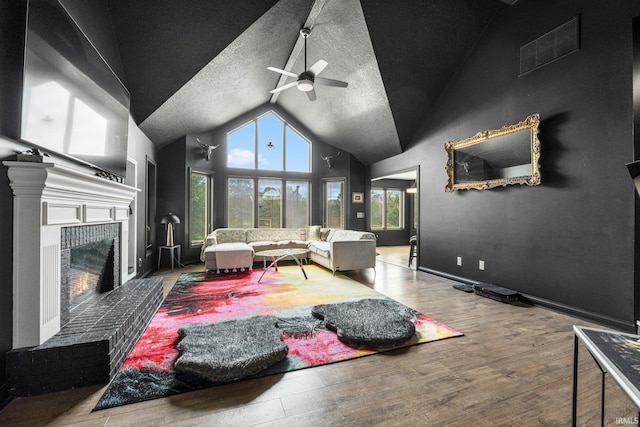 living room featuring vaulted ceiling, a fireplace, ceiling fan, and wood finished floors