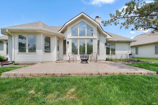 rear view of property featuring a patio area, a chimney, and a shingled roof