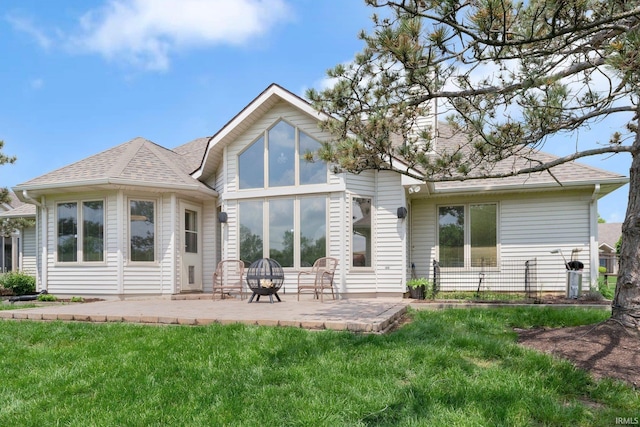 rear view of house with a yard, a patio area, and a shingled roof